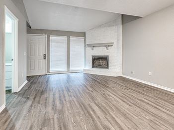 an empty living room with a fireplace and wooden floors